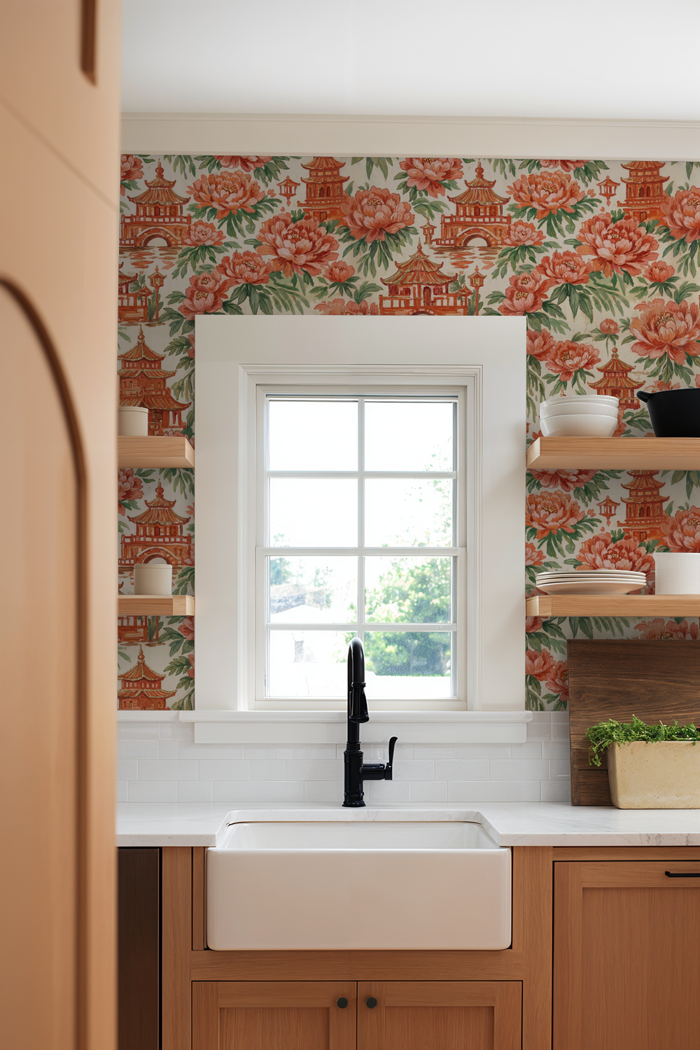 Kitchen with floral wallpaper, window, and wooden cabinets.