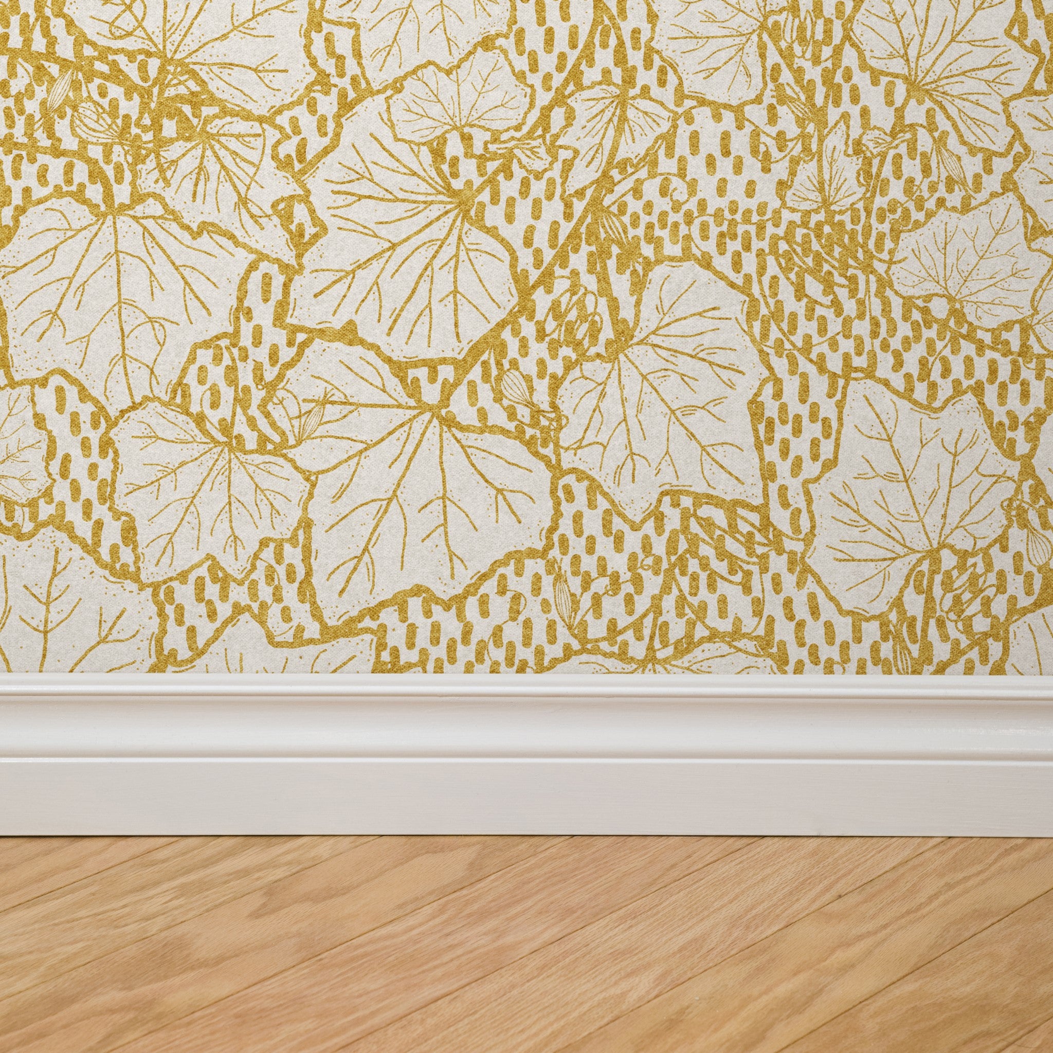 Heath Wallpaper by Wall Blush in a room with detailed golden leaf pattern on lower wall space.
