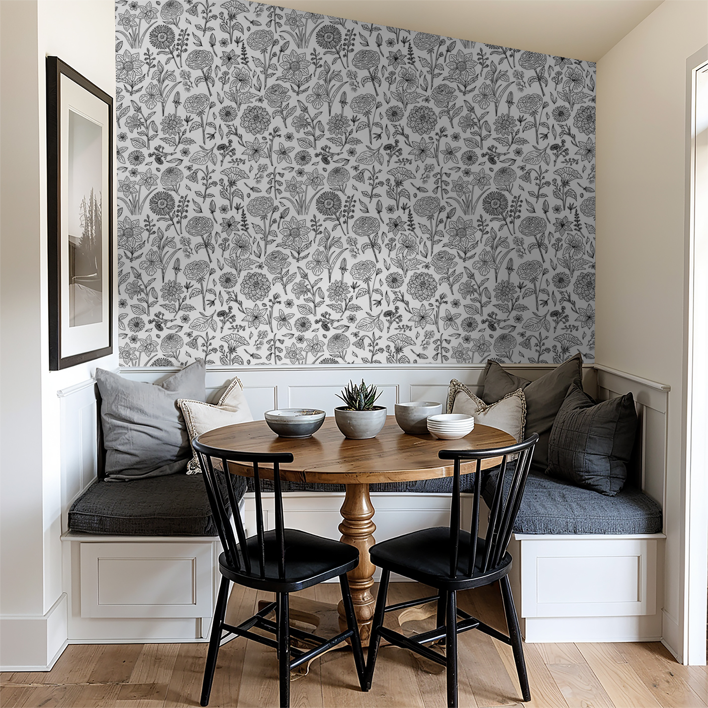 Black and white floral wallpaper in cozy dining nook with wooden table and chairs.