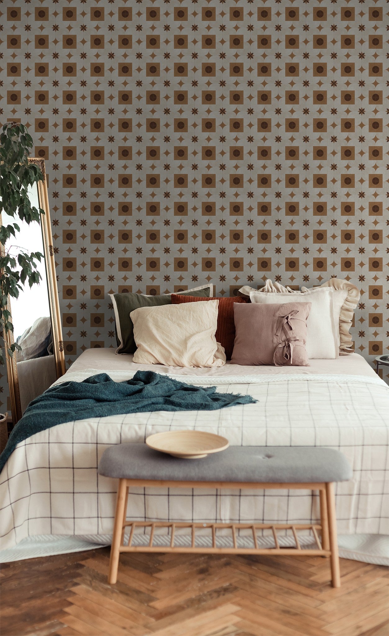 Bedroom with geometric terracotta and cream wallpaper, cozy pillows, and wooden accents.