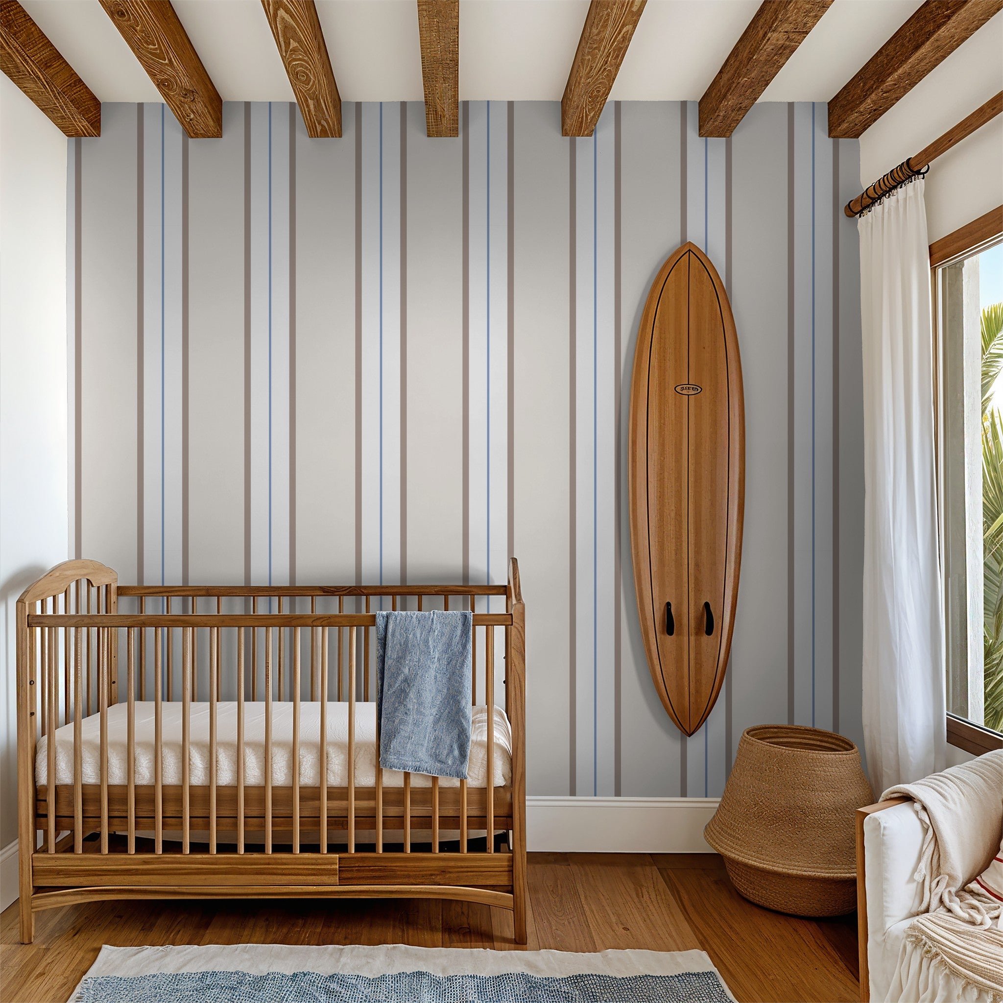 Montclair Stripes blue wallpaper in a cozy nursery with wooden crib and surfboard decor.