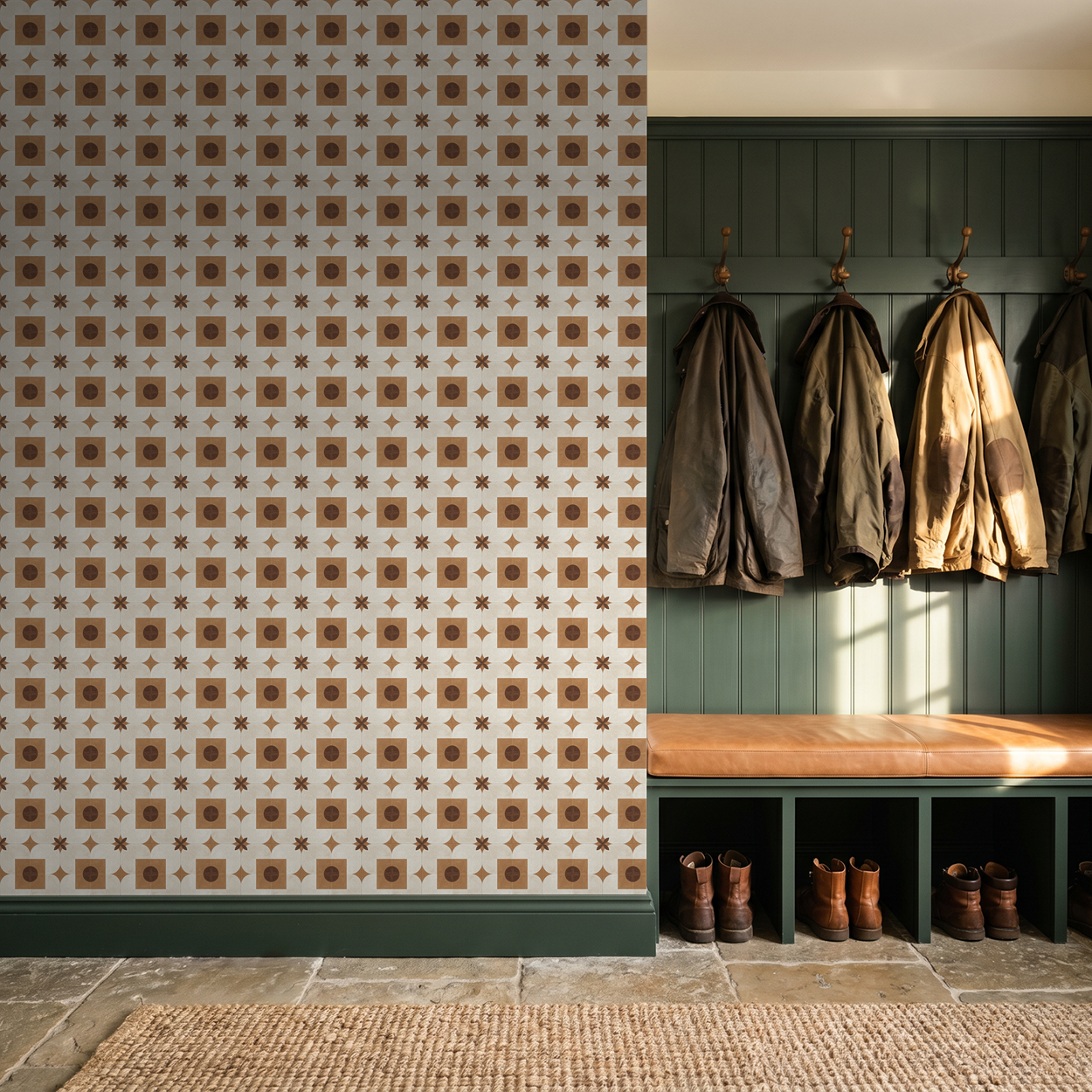 Terracotta and cream geometric wallpaper in a rustic entryway with coats and boots.