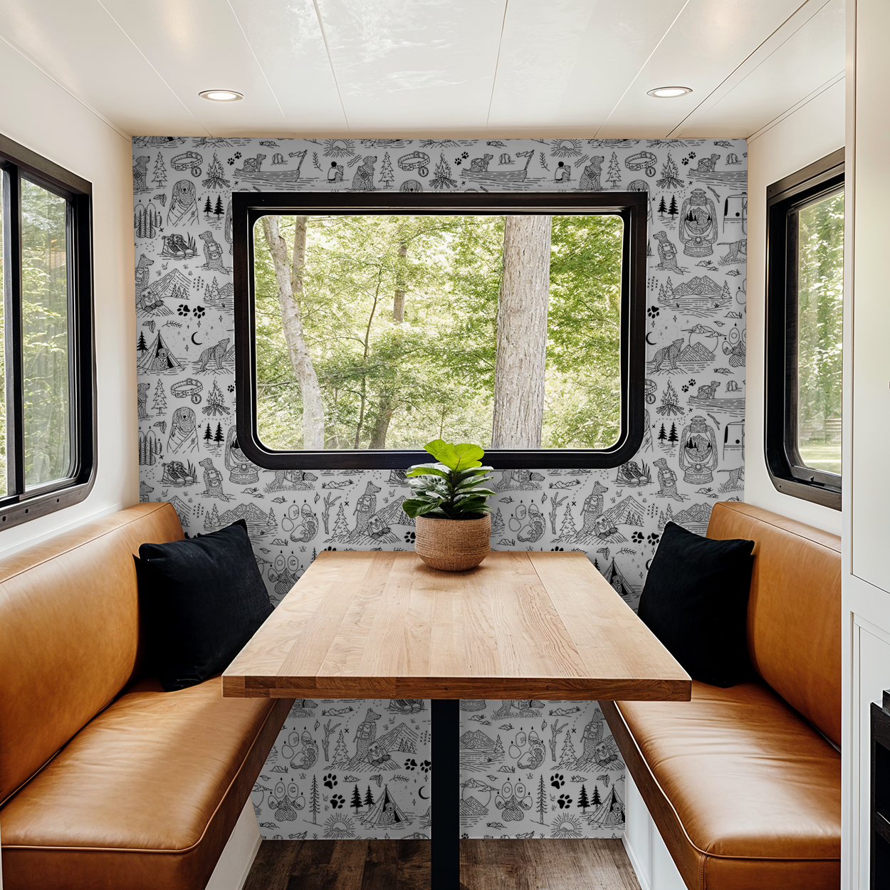 Monochrome dog adventure wallpaper in cozy RV dining nook with leather seating.