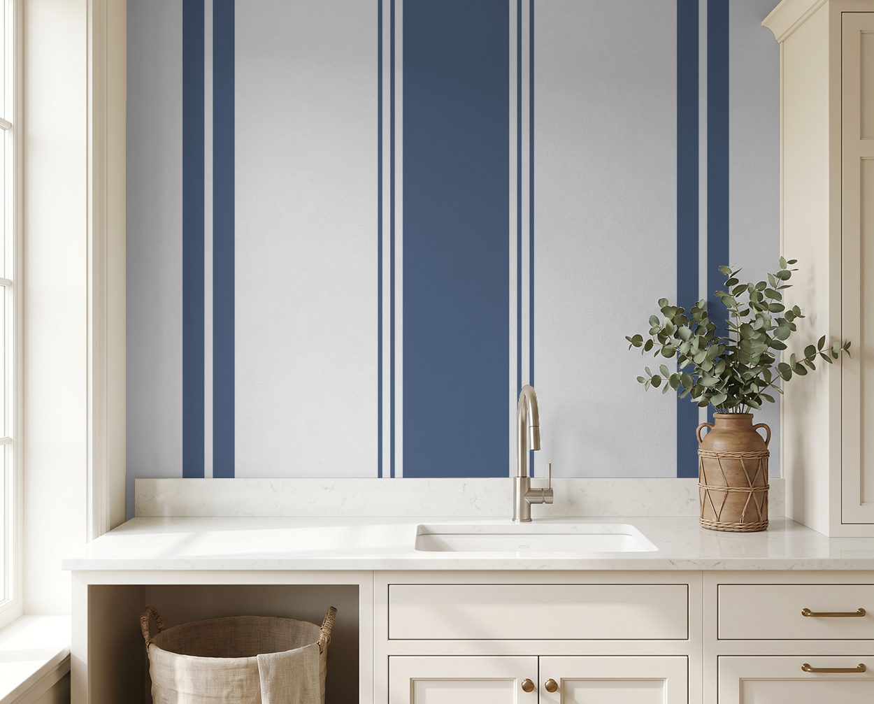 Blue geometric striped wallpaper in modern kitchen with white cabinets and vase.