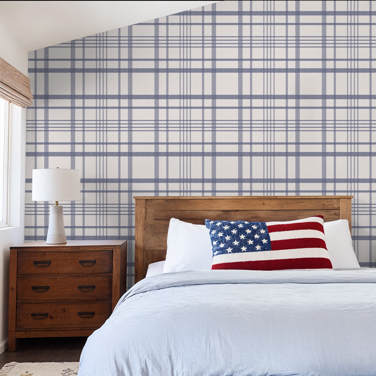 Bedroom with blue plaid wallpaper, wooden furniture, and American flag pillow.