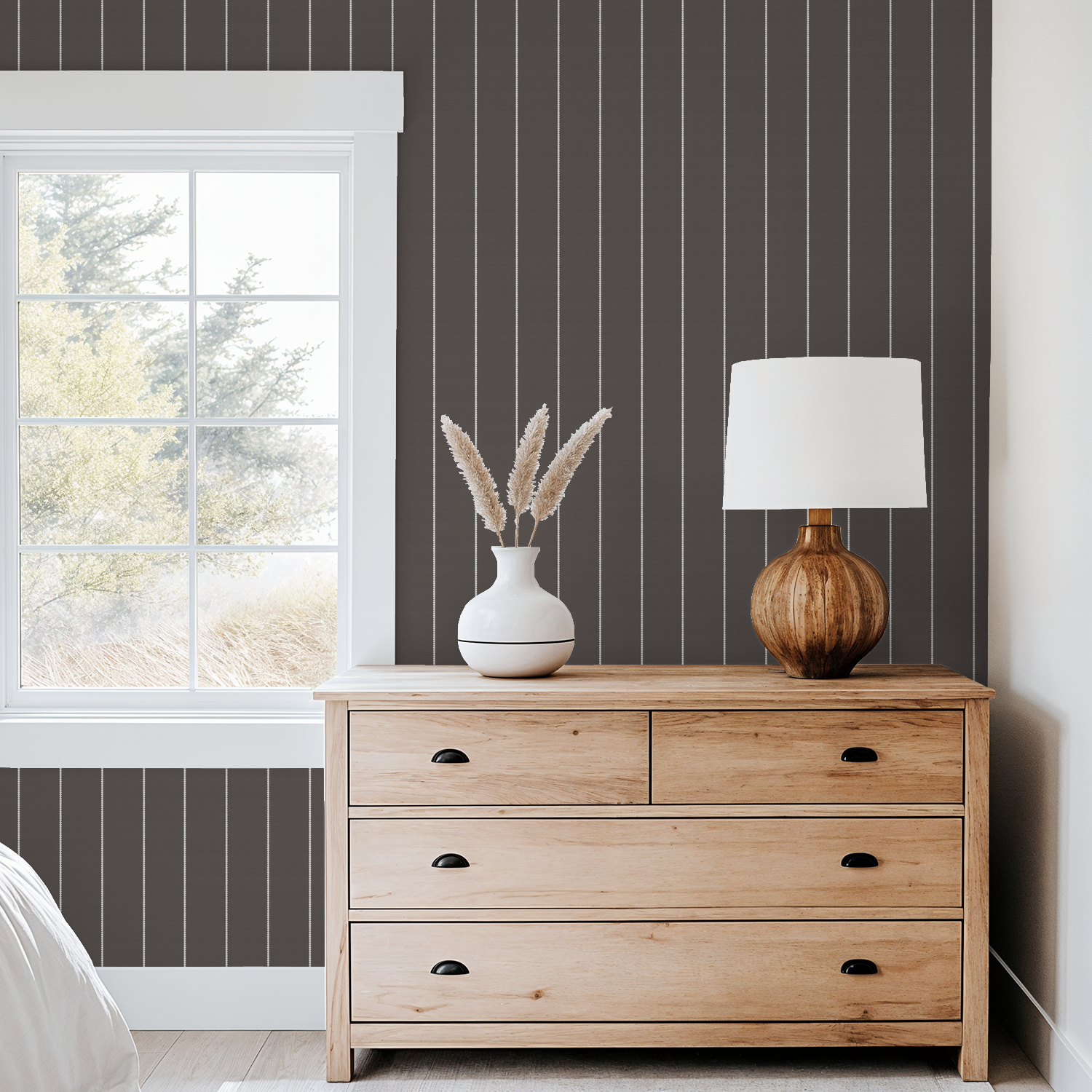 Brown pinstripe dot wallpaper in cozy bedroom with wooden dresser and lamp.