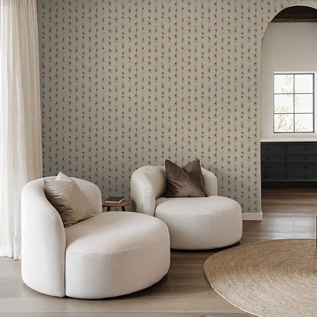 Cream wallpaper with red floral vines in a cozy living room with white chairs.