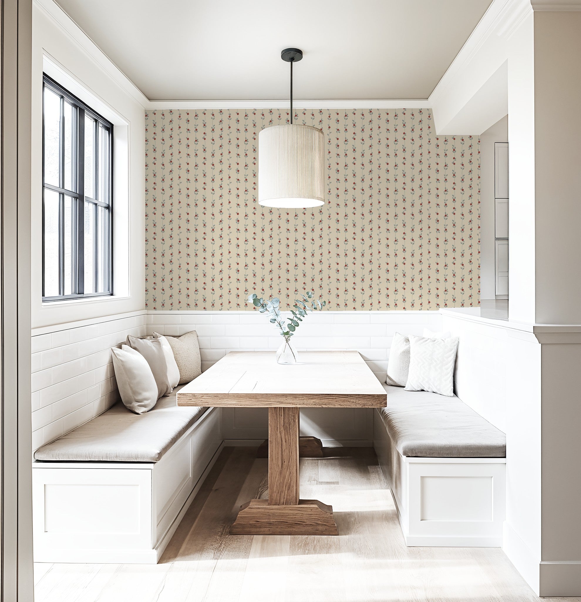 Cream wallpaper with red floral vines in cozy dining nook with wooden table.
