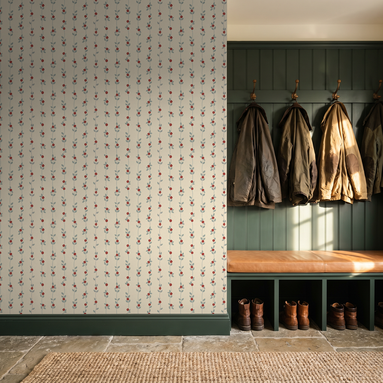 Cream wallpaper with red floral vines in rustic entryway with coats and boots.
