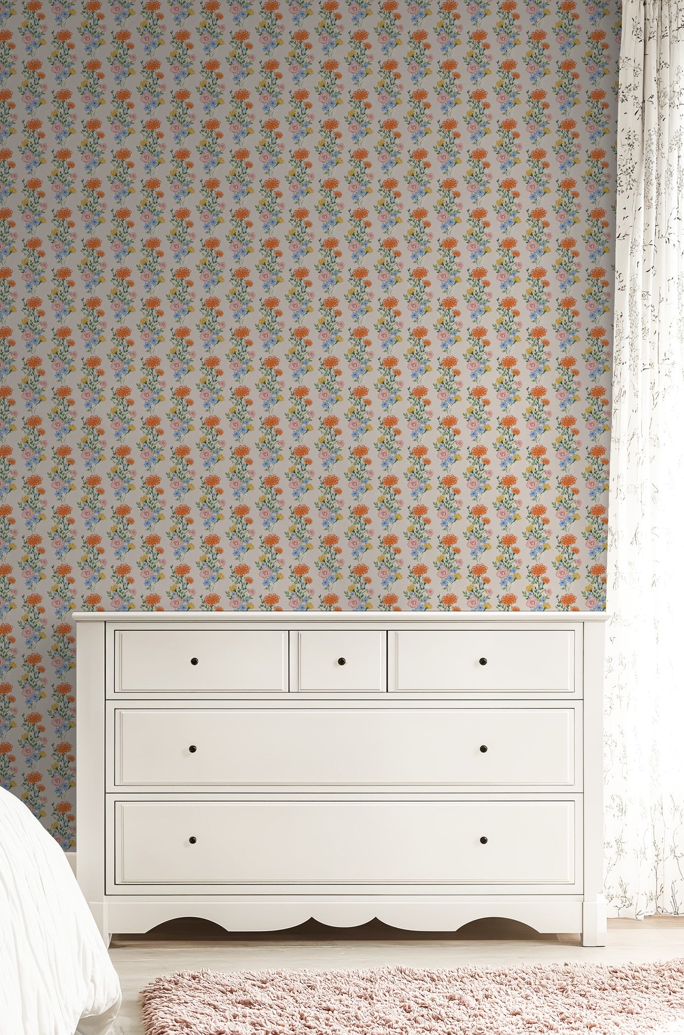 Eden Fields floral wallpaper with vibrant orange, pink, and blue flowers in a cozy bedroom setting.