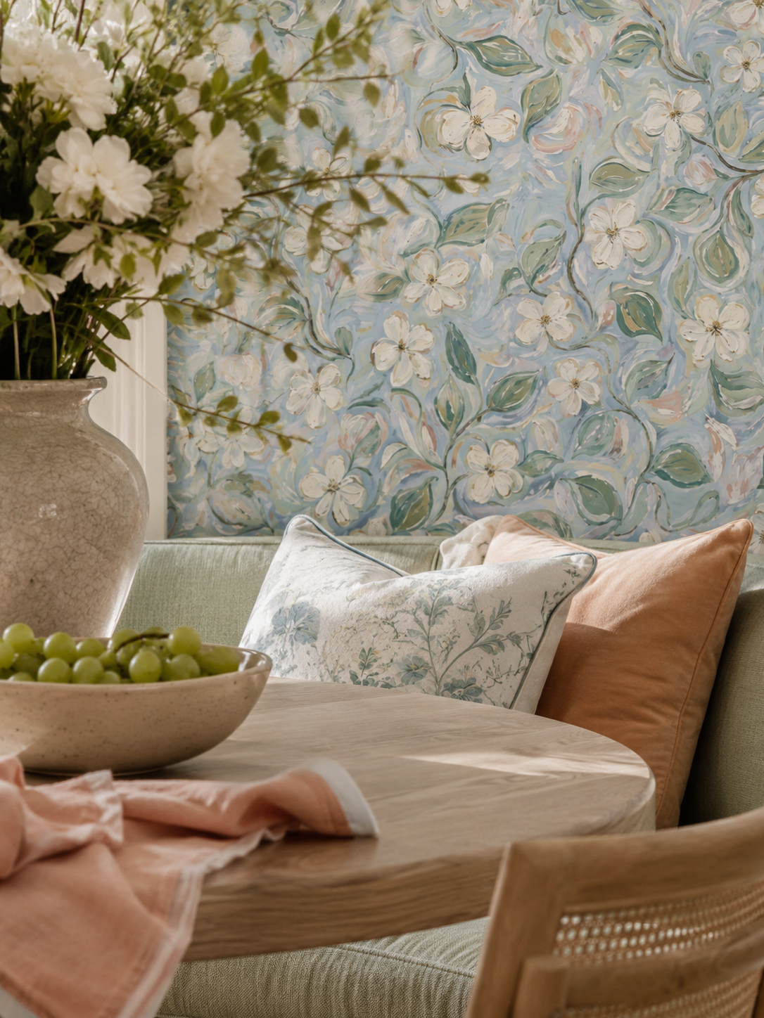 Floral wallpaper with white flowers, soft blues and greens in cozy dining room setting.