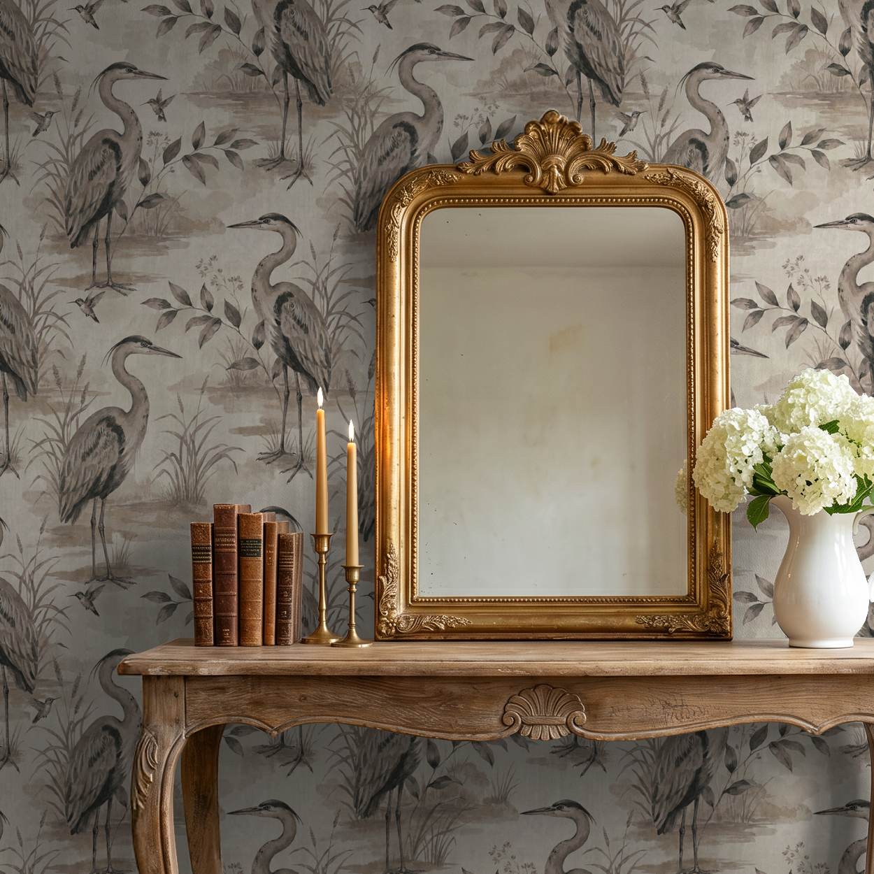 Heron Lake wallpaper with herons and foliage in taupe tones behind vintage mirror and table.