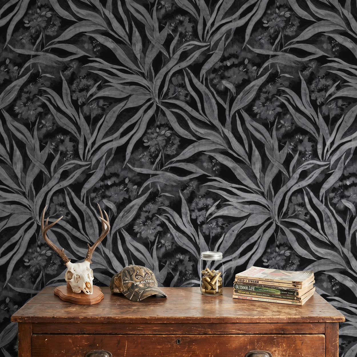 Monochrome foliage wallpaper with grey leaves on dark background in rustic room.