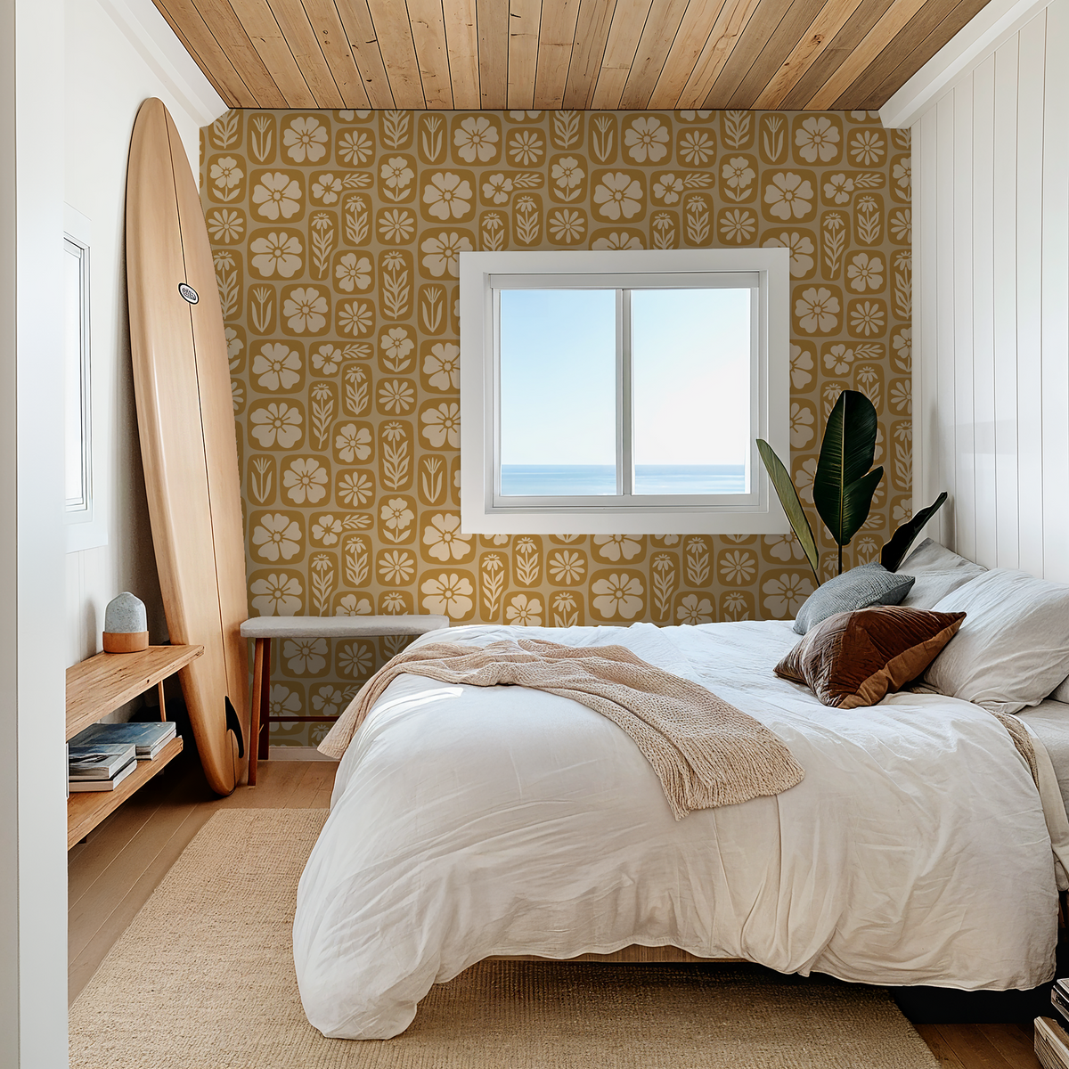 Mustard floral wallpaper in cozy bedroom with surfboard and ocean view.