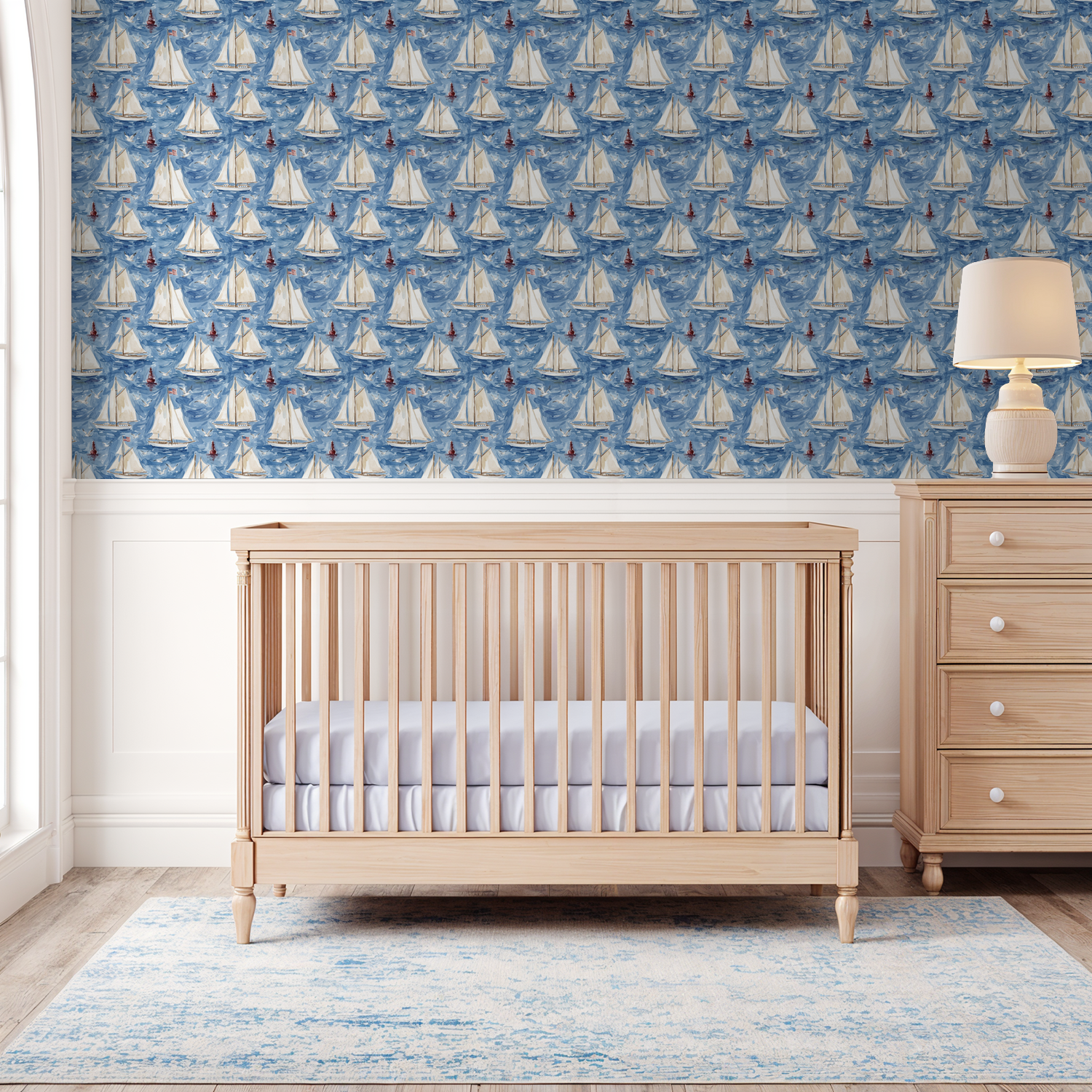 Nautical wallpaper with sailboats in a blue nursery setting with crib and dresser.