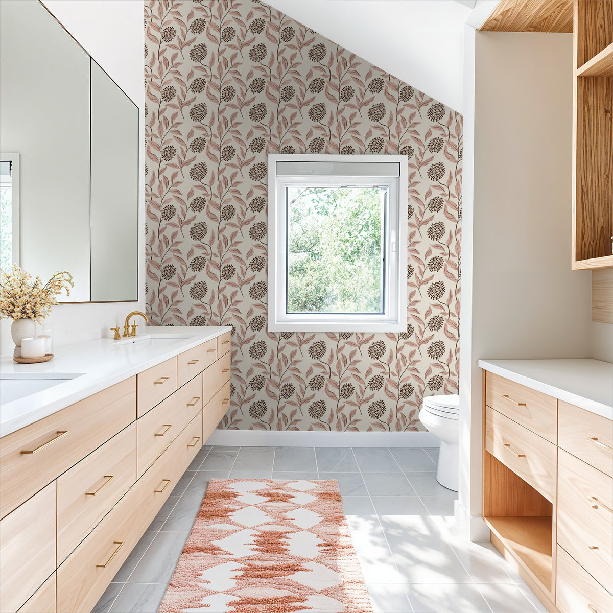 Bathroom with pink botanical wallpaper, light wood cabinets, and white countertops.