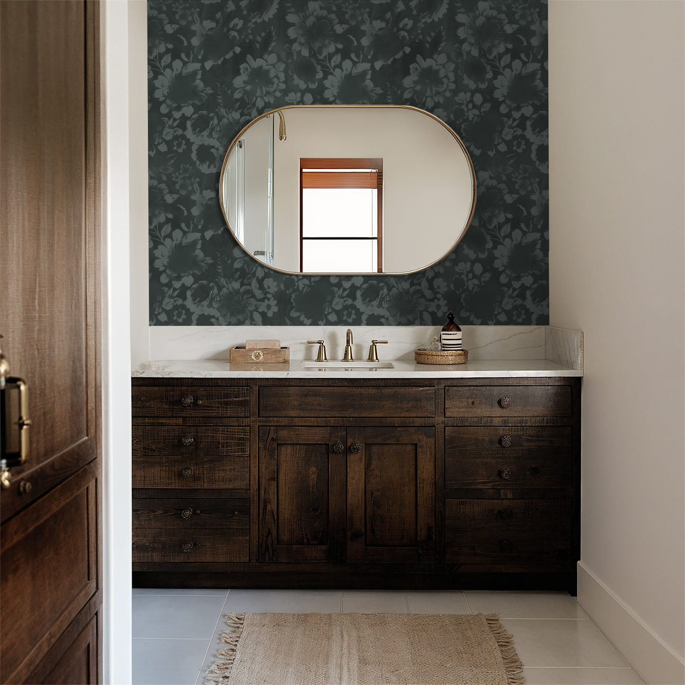 Teal floral wallpaper in elegant bathroom with wooden vanity and oval mirror.