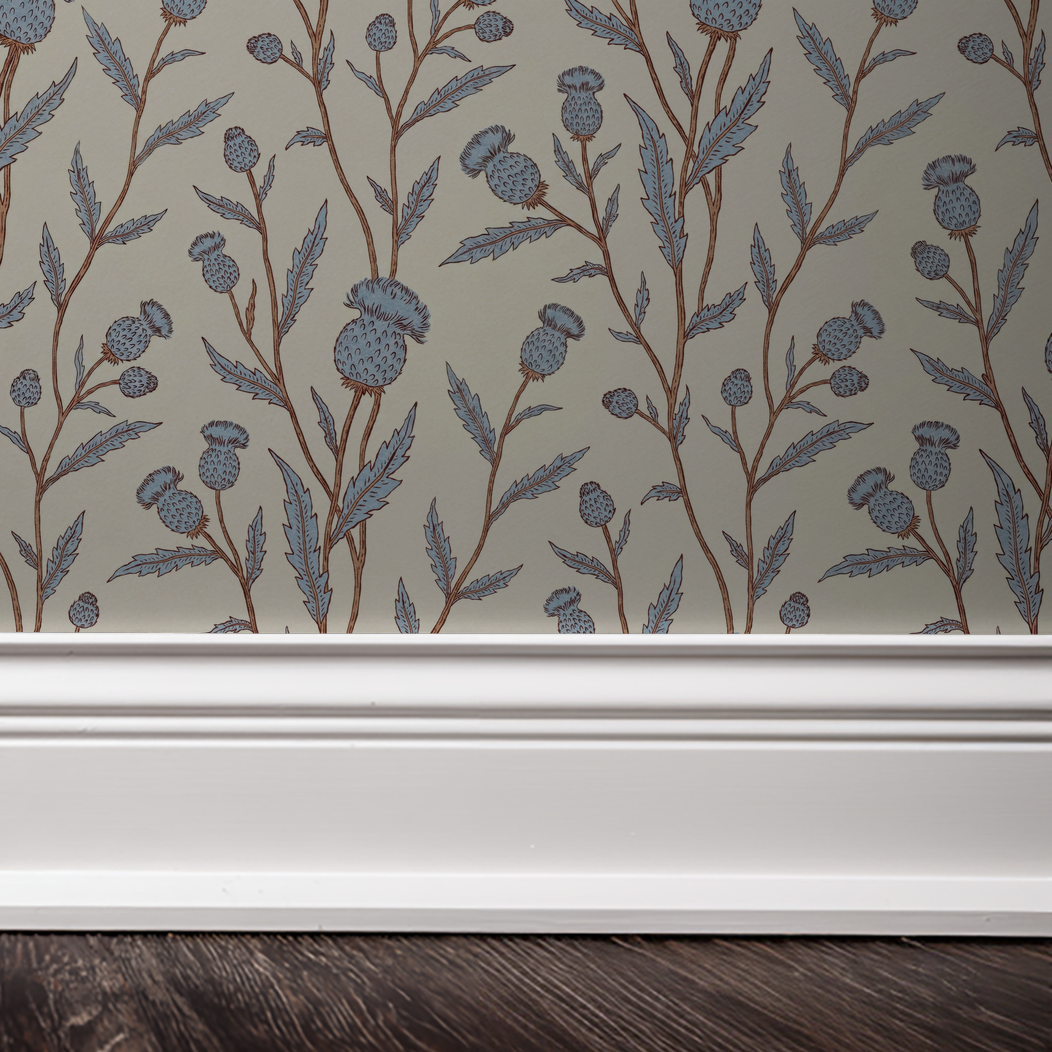Thistle motif wallpaper in blue and brown with white trim and dark floor.
