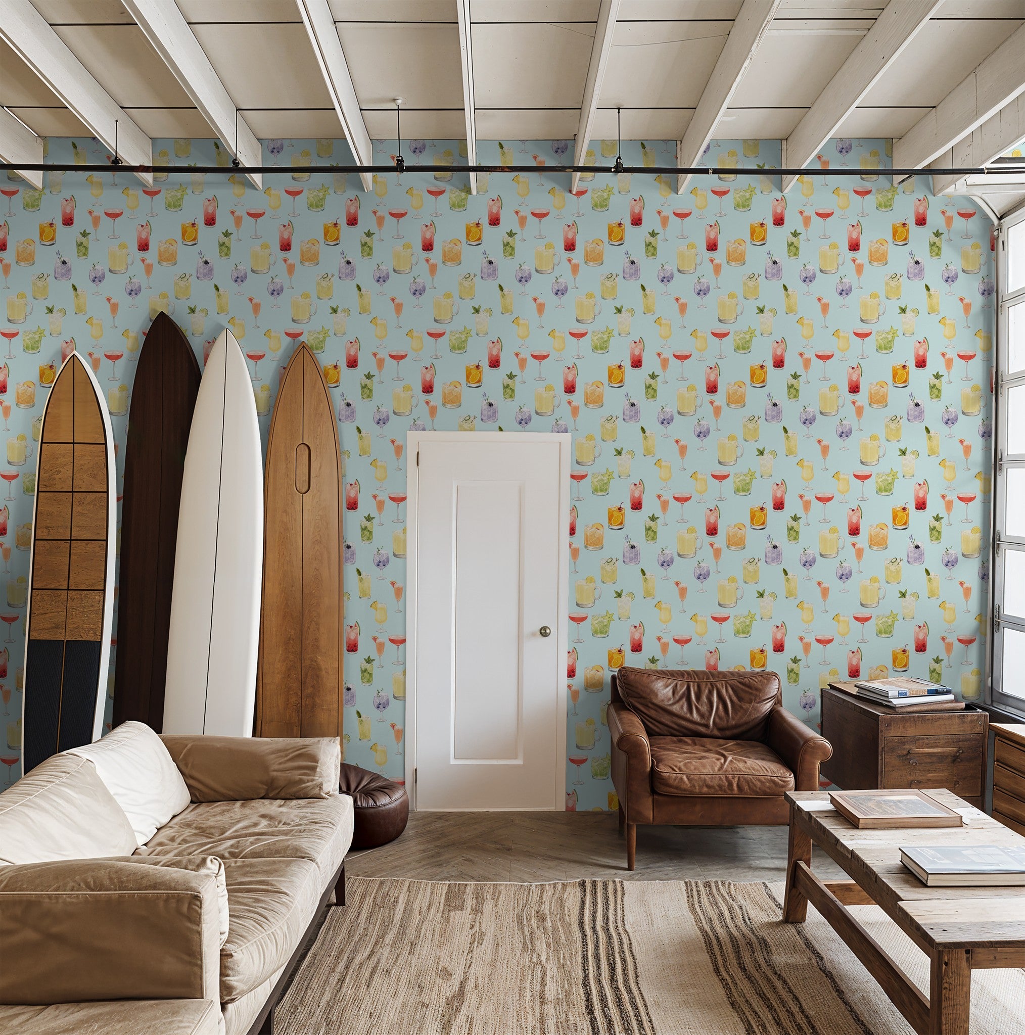 Vibrant cocktail pattern wallpaper in cozy living room with surfboards and leather chairs.